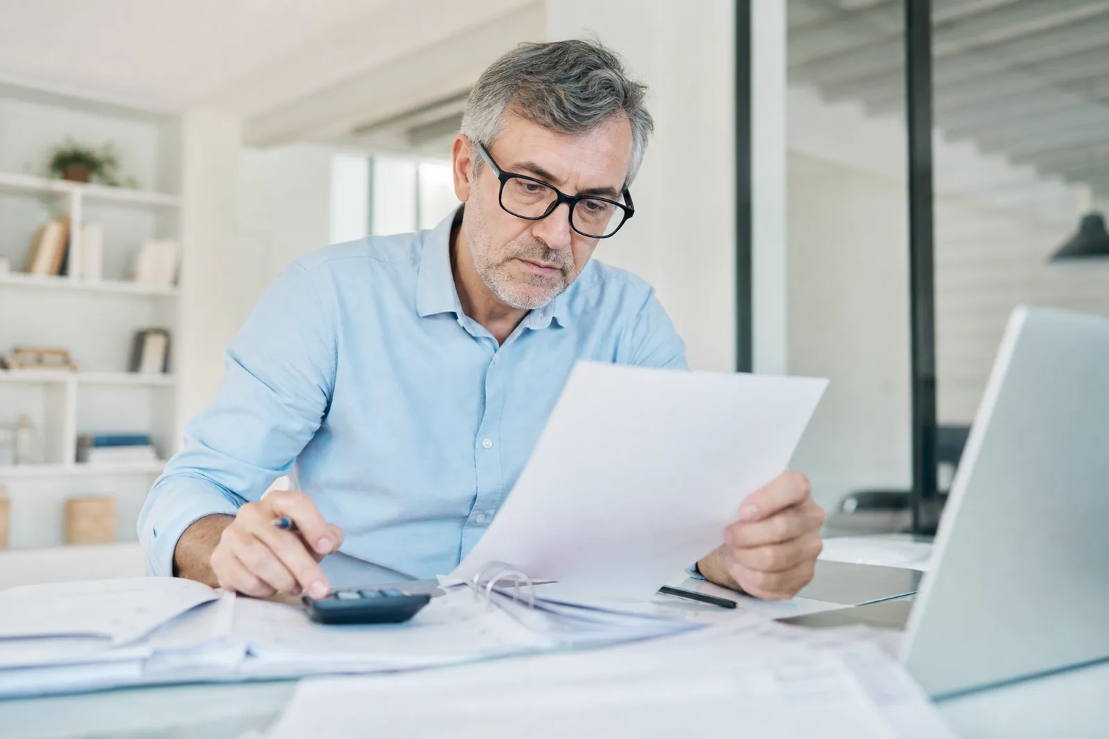 Entrepreneur consultant ses documents fiscaux et sa déclaration de CFE sur un bureau lumineux.