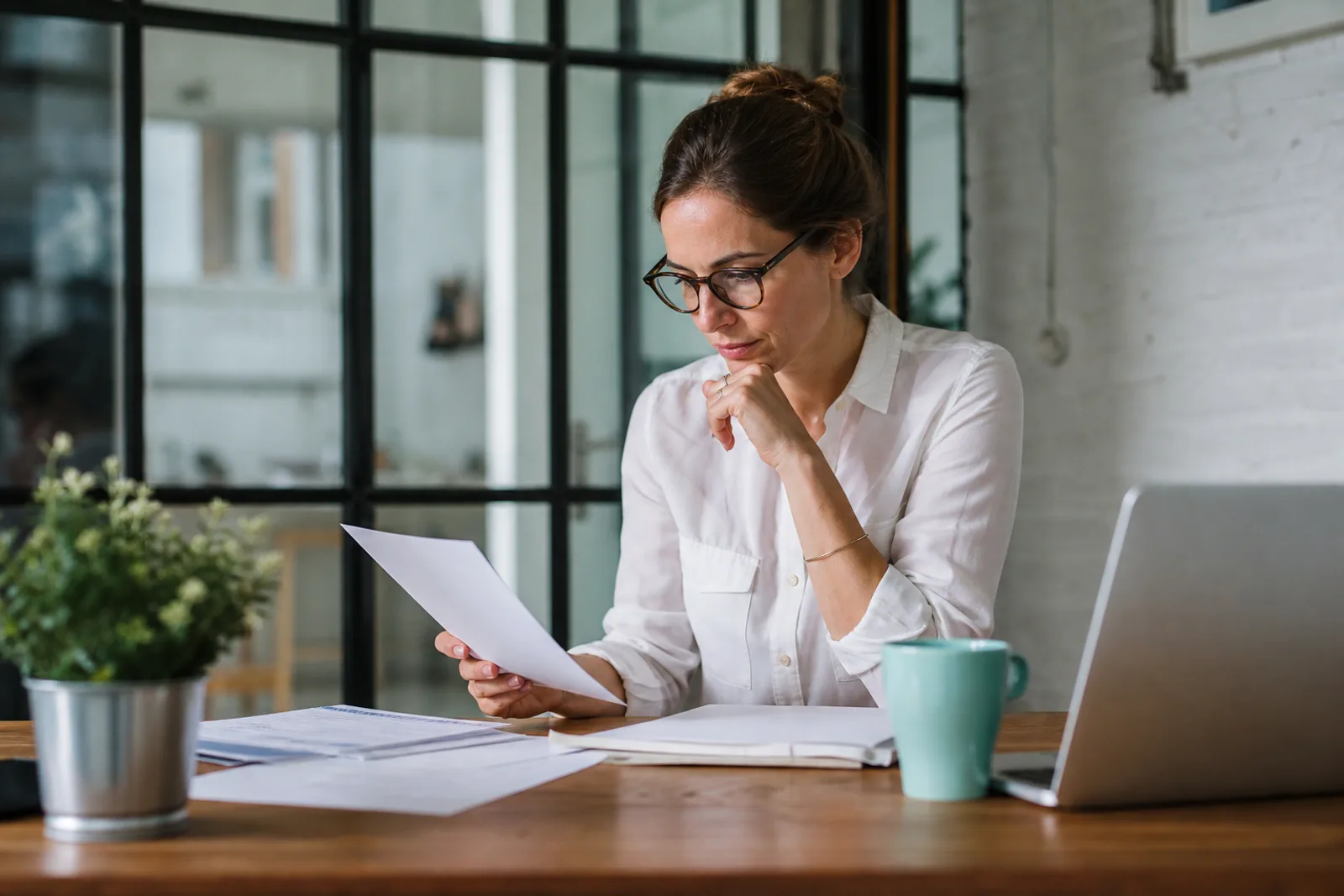 Auto-entrepreneur préparant une facture sur son ordinateur portable dans un espace de travail lumineux.