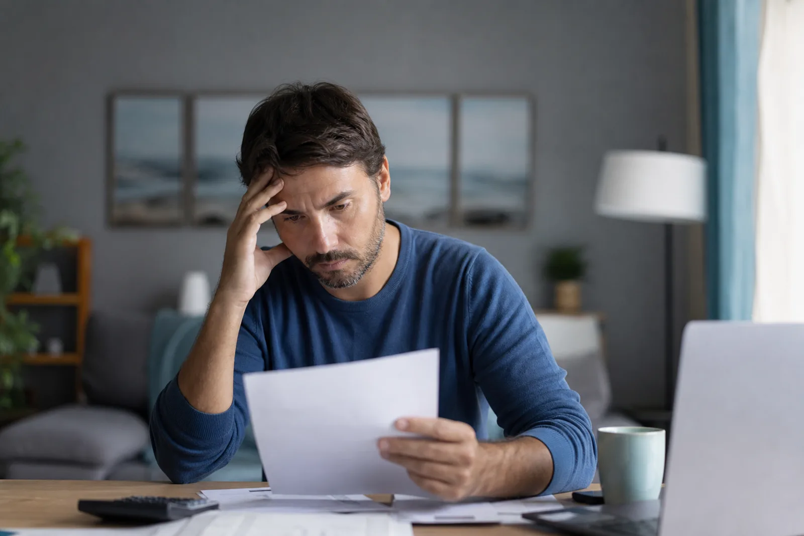 Personne consultant des factures impayées et des courriers de relance à son bureau.
