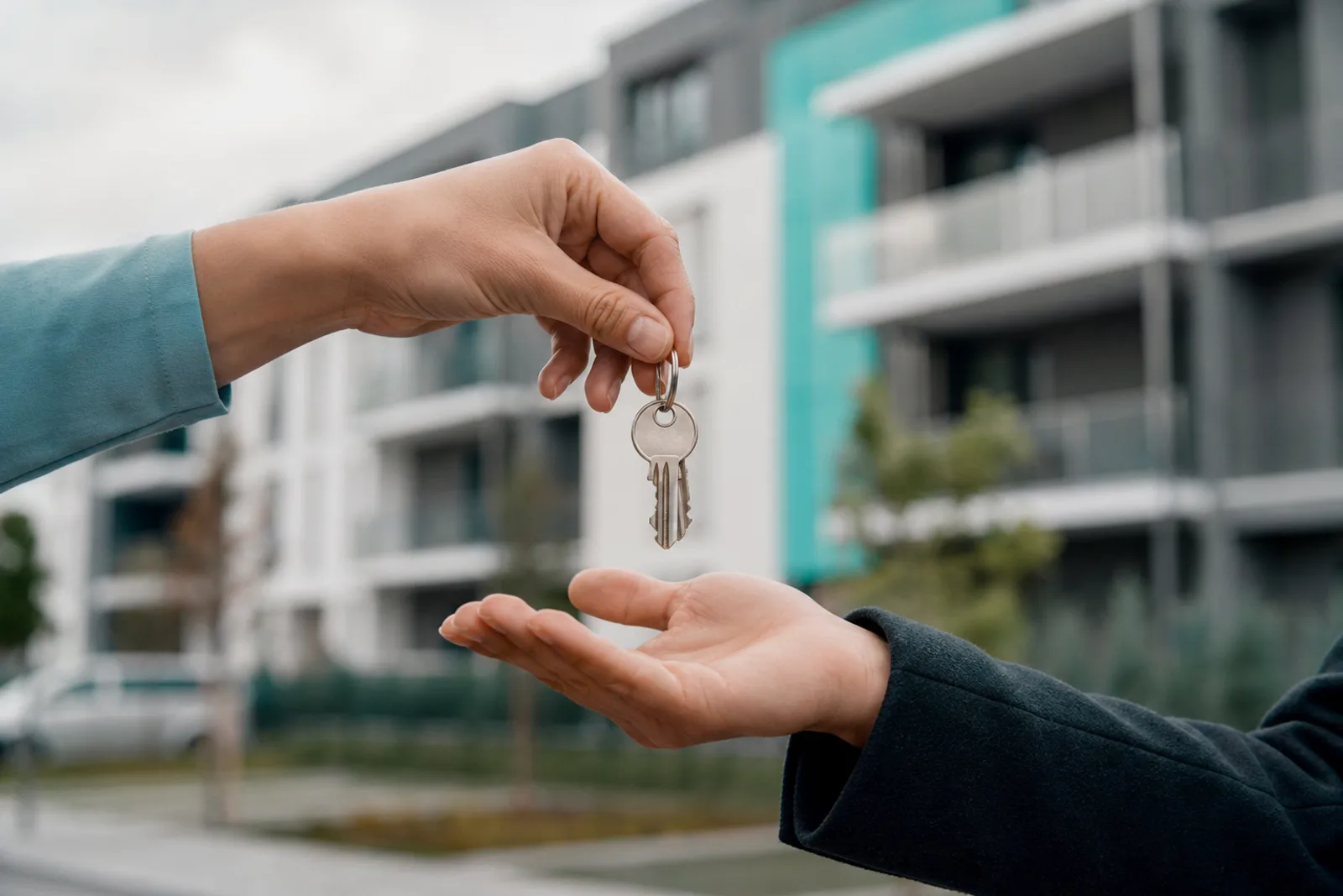Remise des clés d'un nouvel appartement devant un immeuble résidentiel moderne.