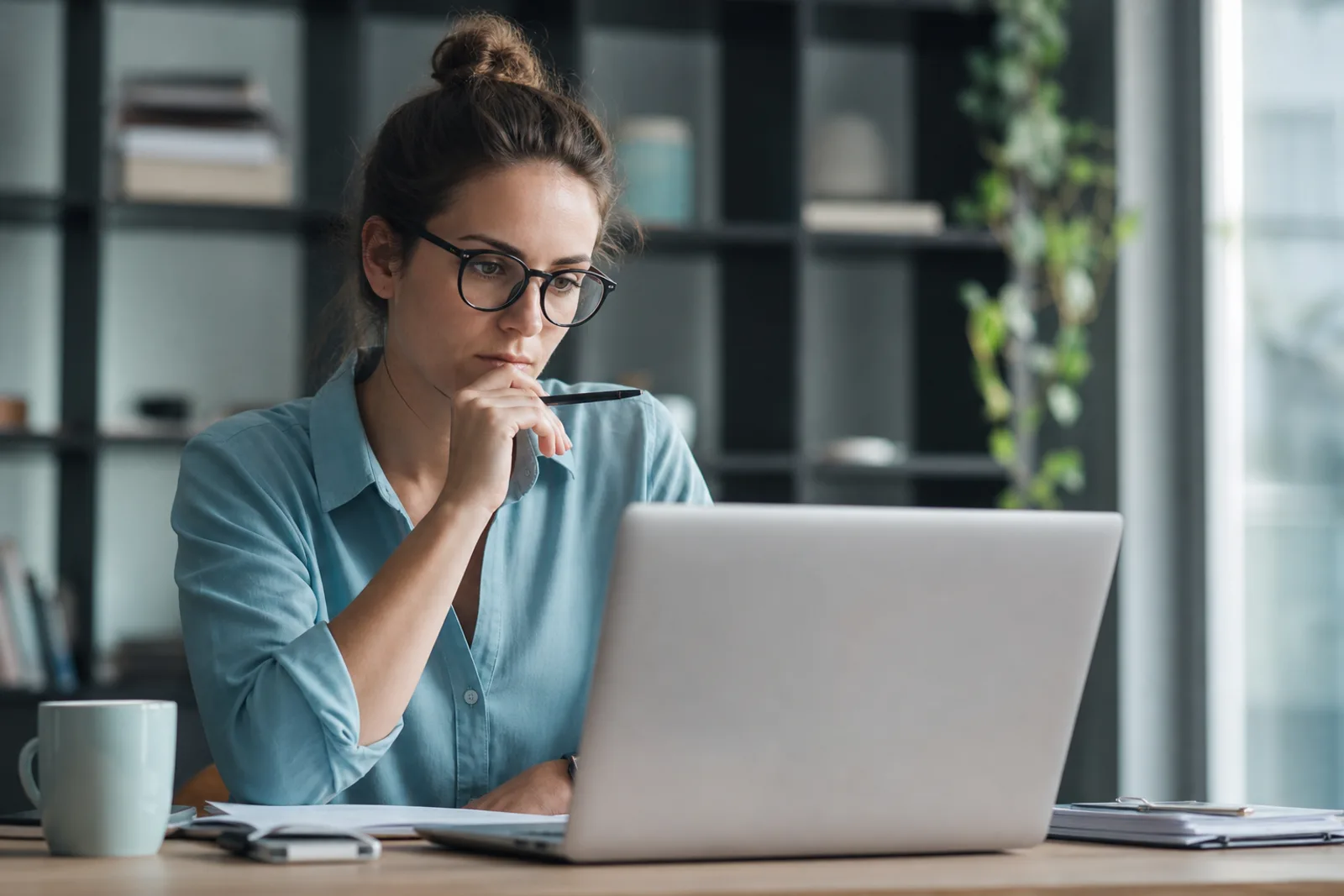 Un auto-entrepreneur consultant ses factures et son chiffre d'affaires sur un ordinateur portable, à son bureau.