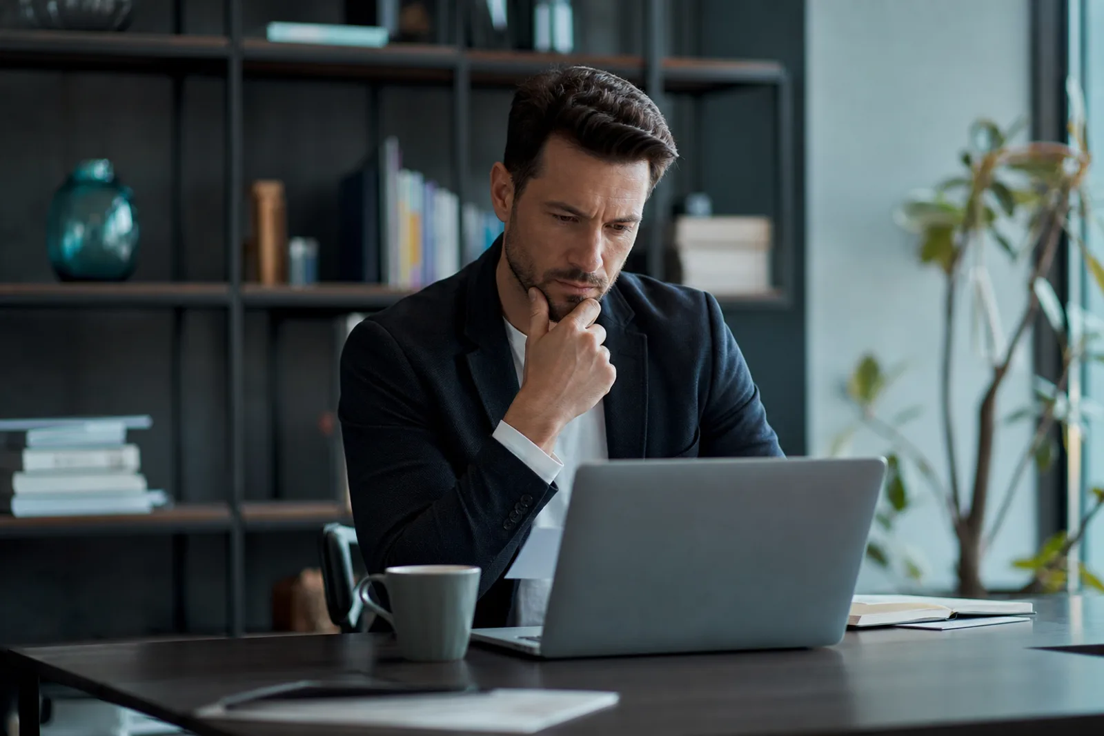 Consultant freelance travaillant sur un ordinateur portable à son bureau, dossiers et documents administratifs à côté.