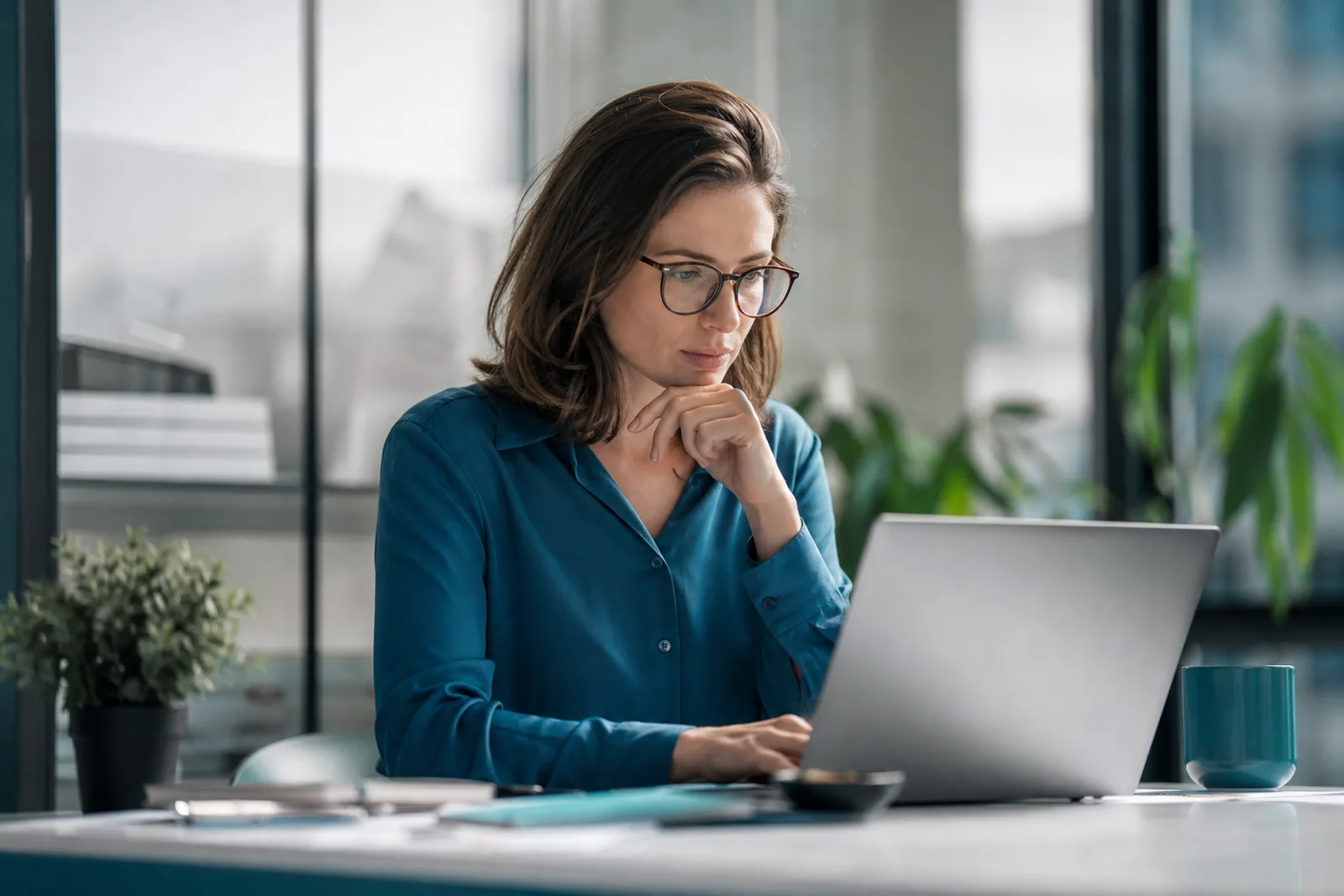 Entrepreneure concentrée devant son ordinateur portable dans un bureau lumineux.