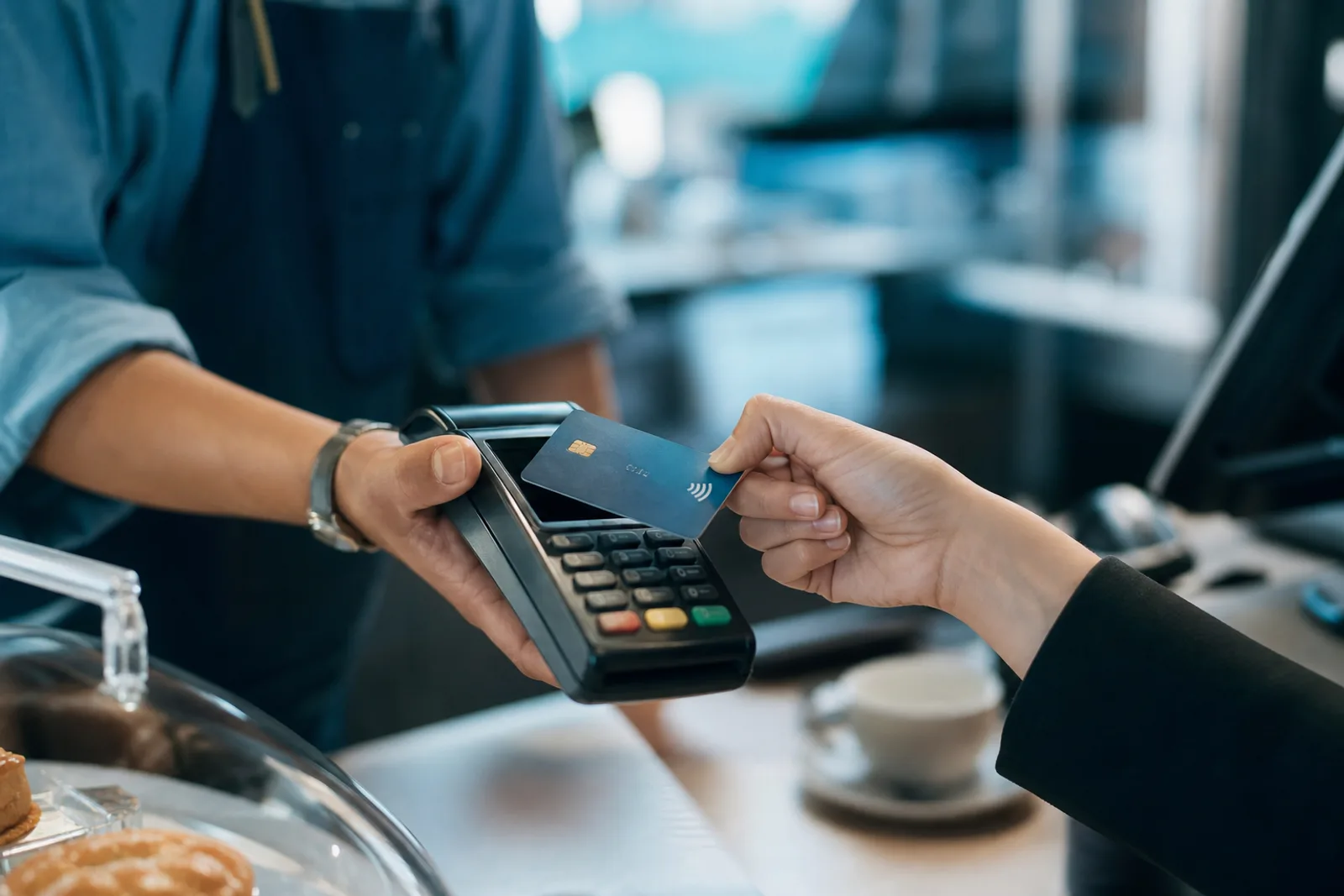Personne payant avec sa carte bancaire sans contact sur un terminal de paiement.